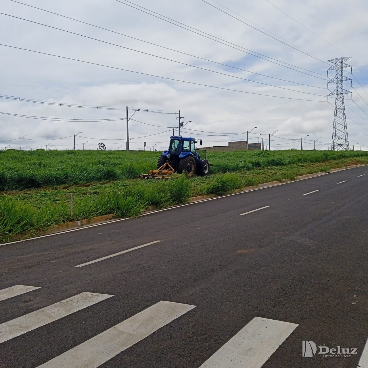 Trator com roçadeira acoplada trabalha na faixa junto à rodovia