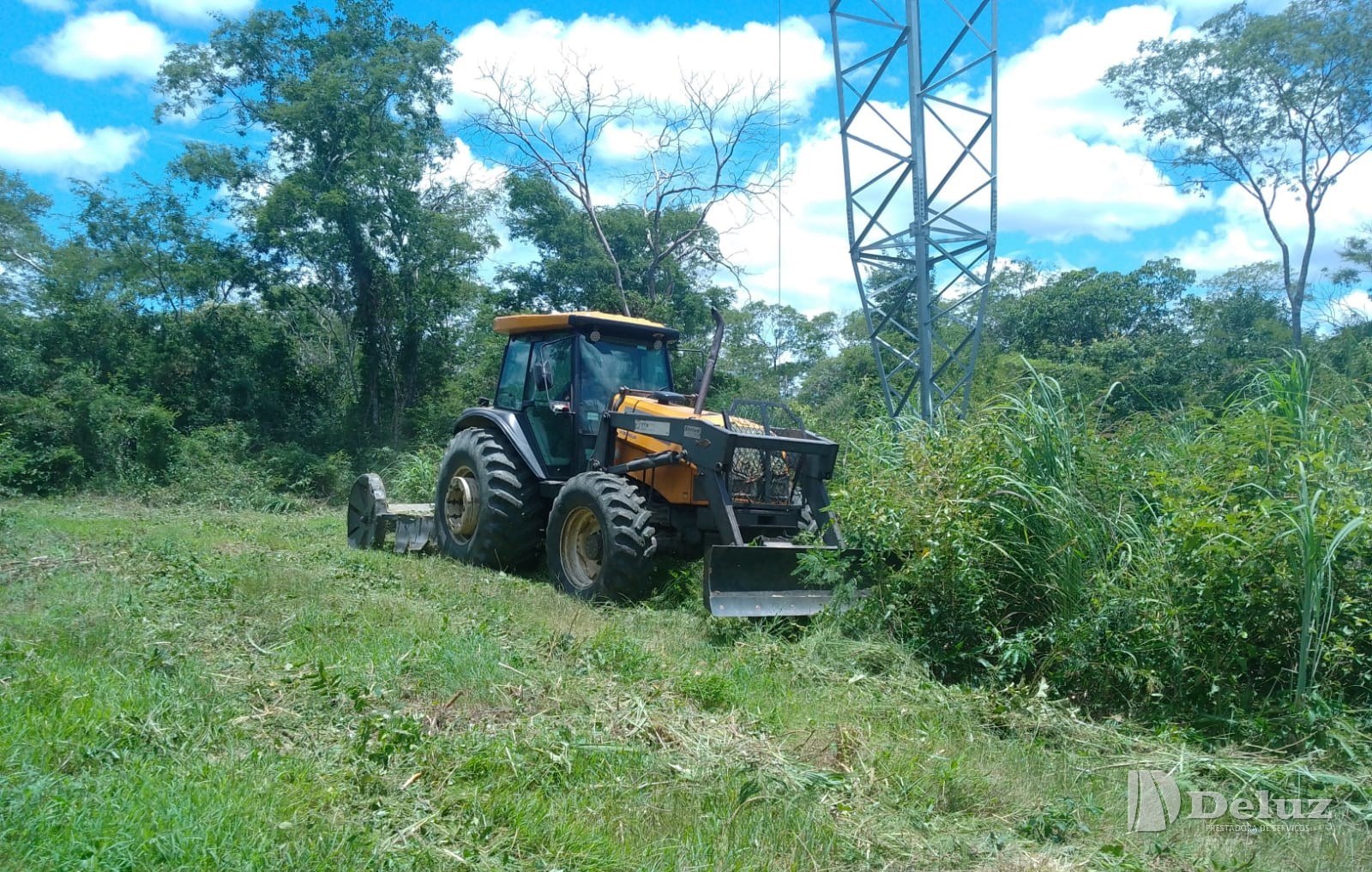 Roçadeira acoplada ao trator, trabalhando ao pé da estrutura