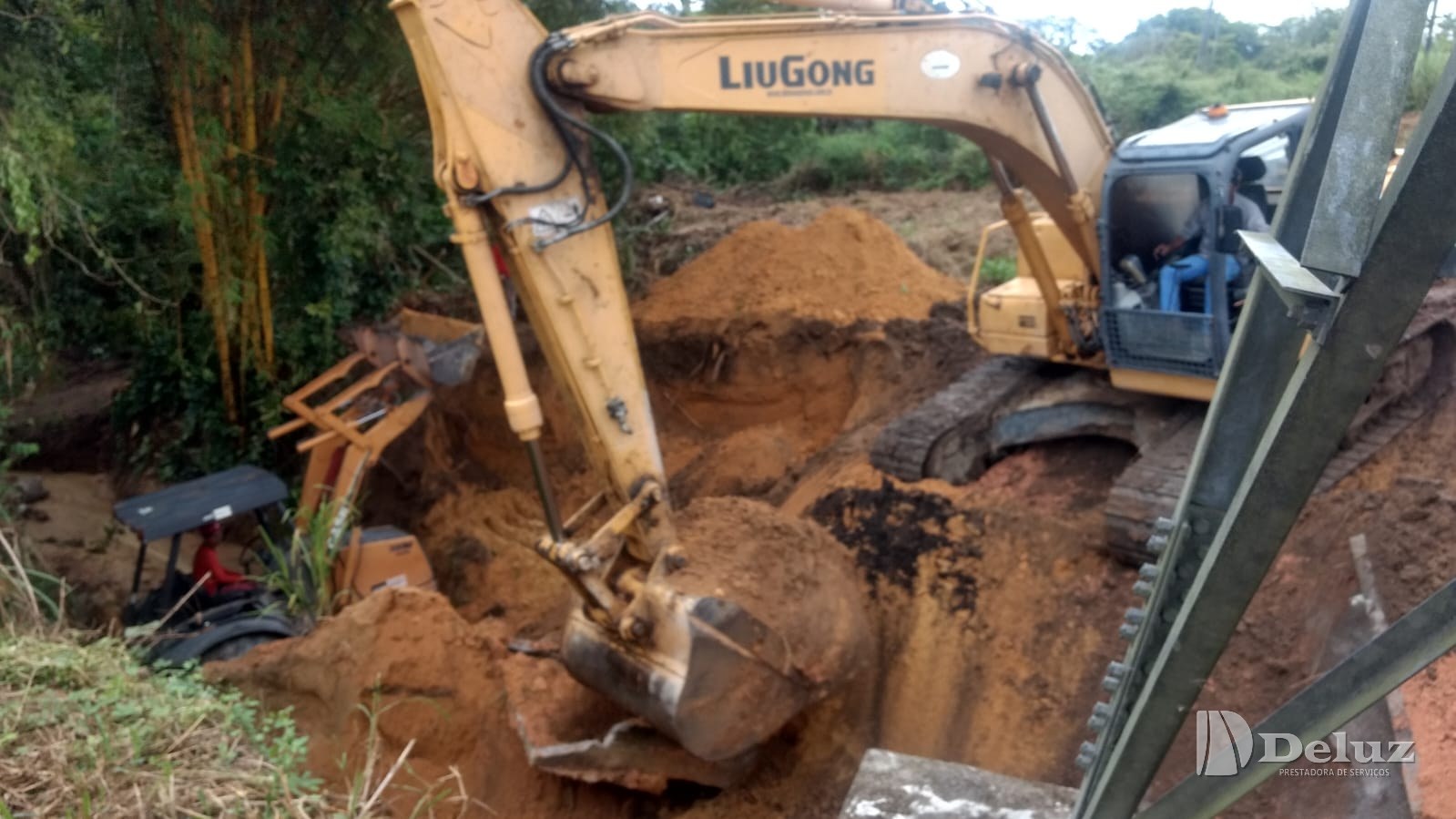 Escavadeira reconforma o terreno junto à estrutura