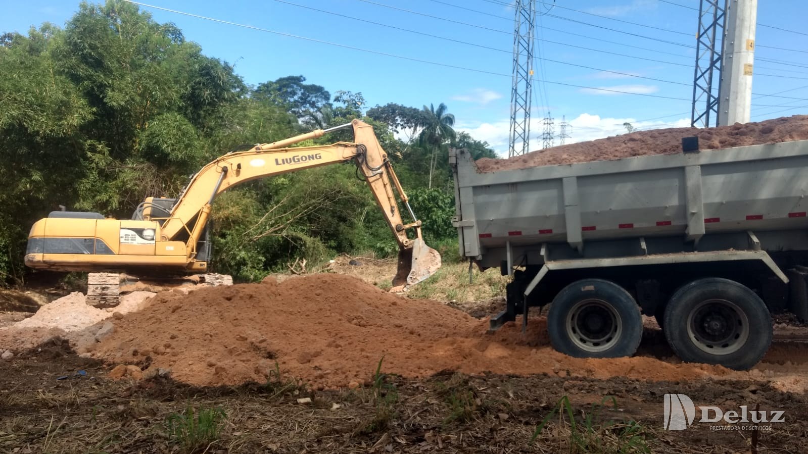 Escavadeira carrega caminhão basculante com o material retirado