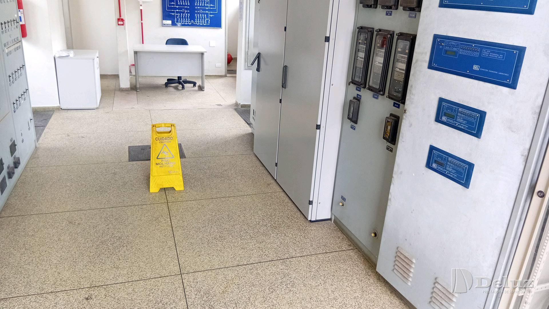 Corredor de painéis elétricos limpo, com placa de sinalização de piso molhado