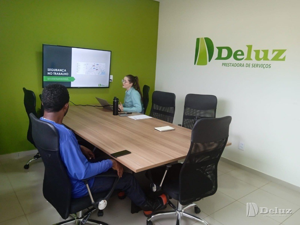 Sala de reunião da nova sede, com televisão exibindo uma apresentação de segurança do trabalho