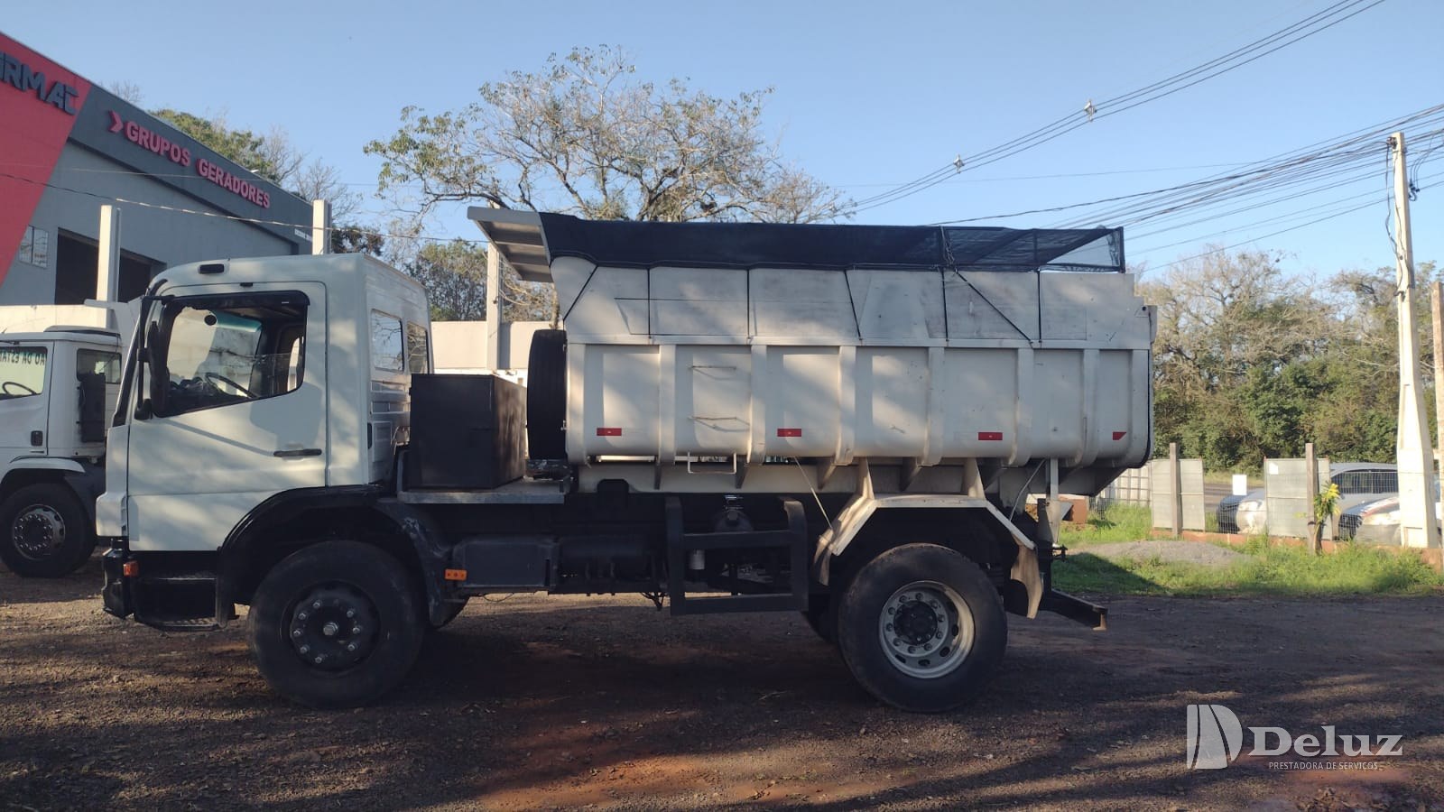 Caminhão basculante de laterais altas, com cobertura de tela, usado no transporte do material triturado