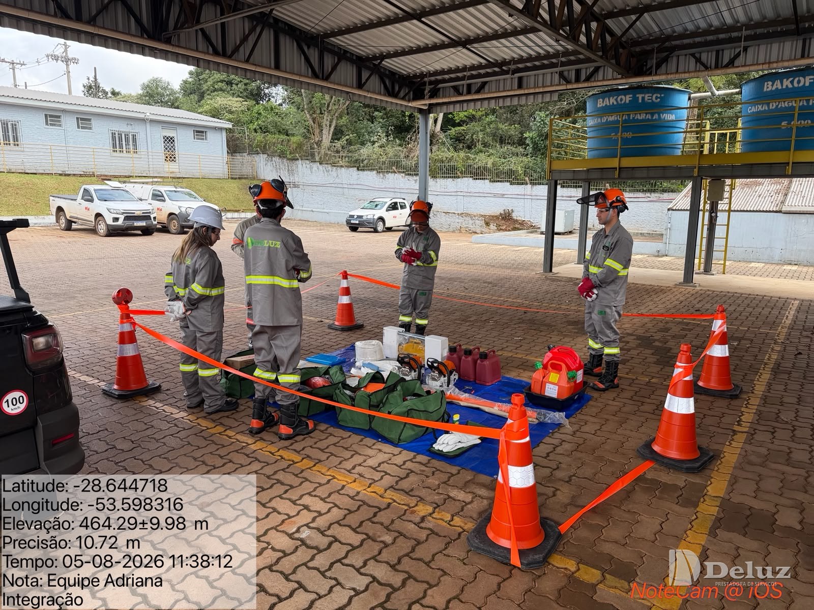 Equipe da Deluz de uniforme e capacete com viseira, ao redor do material estendido em lona, em área isolada por cones e fita